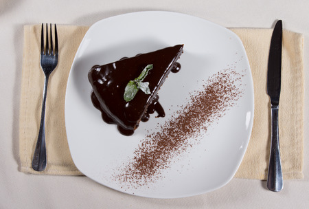 Overhead view of a slice of rich tasty freshly baked chocolate cake with icing dripping down the sides served on a plate at tableの写真素材