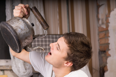 Close up Young Handsome Man Drinking From Vintage Kettle Inside a Room.