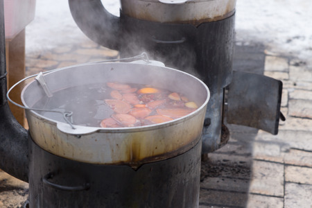 Food cooking on an outdoor wood burner stove on a paved surface with winter snow , high angle view of the steaming pot and foodの写真素材