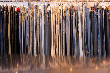 Clothes hanging on a rail in a shop or fashion boutique in a retail and sales conceptの写真素材