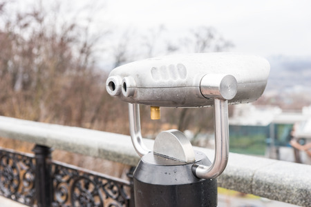 Viewing telescope mounted alongside ornate wrought iron railings overlooking a town and view for tourists to view the landscape at a distanceの写真素材