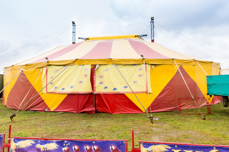 Exterior view of a colorful yellow and red marquee erected in a field for a circus or traveling theatre act at a fairgroundの写真素材