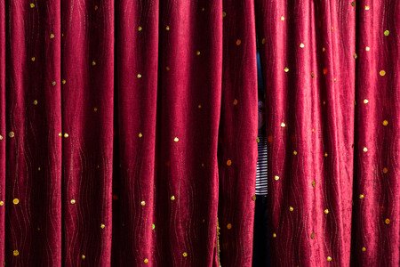 Little boy lurking behind the stage curtains peering through the gap waiting for his cue to come out on stage during a performanceの写真素材
