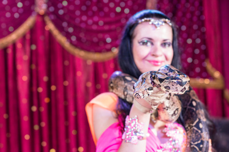 Head and Shoulders Close Up Portrait of Exotic Dark Haired Snake Charmer Wearing Large Snake Around...