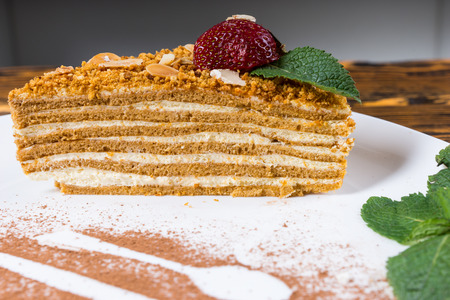 Tasty speciality layered tart with biscuit and cream topped with a fresh strawberry served on a plated with chocolate powder decorationの写真素材