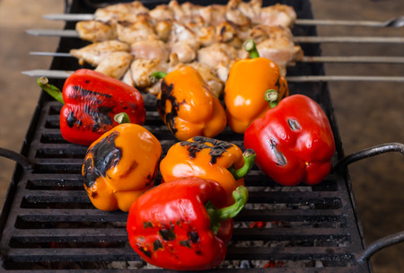 Close Up of Grilling Fresh Whole Red and Orange Peppers and Meat Skewer Kebabs on Outdoor BBQ Grillの写真素材