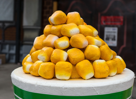 Stack of freshly baked bread rolls in the form of a pyramid displayed on a round table at a catered event or fairgroundの写真素材