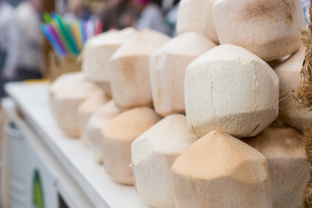 Close Up of Prepared Coconuts, Husked and Carved, Stacked on Beverage Cart at Food Festival Eventの写真素材