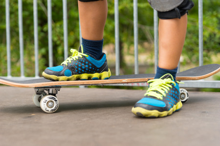 Feet of a skateboarder on a ramp at the skate park wearing a pair of trendy blue sneakers with yellow laces, close up viewの写真素材