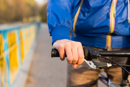 Young man riding a bicycle with a close up detail view of his hand on the brake lever on the handlebarsの写真素材