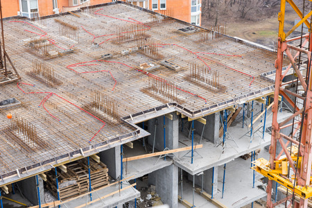 Unfinished apartment floor with steel rods and concrete under construction with wood high up in the...