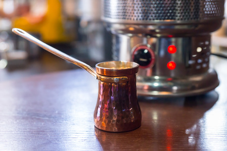 Special long handled jug for preparing the milk for cappuccino coffee on a counter in a restaurant in front of a coffee machineの写真素材