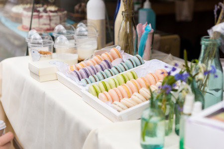 Flavored colorful French macarons or macaroons on a sale at a market stall arranged neatly by color on a trayの写真素材