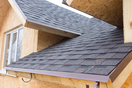 Detail of overlapping roofing tiles on a new build wooden house with dormer windows