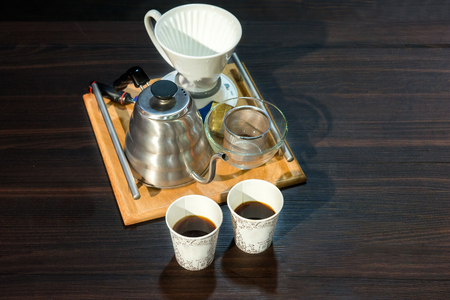 Traditional, manual filter coffee set with a metal jug and white ceramic filter viewed high angle with two cups of fresh black coffee alongsideの写真素材