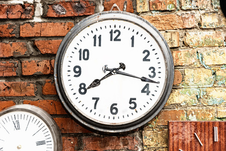 Close Up of Clock Hanging on Exterior Brick Wall Displaying Time of Quarter Past Eightの写真素材