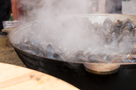 Mussels steaming in a large commercial open-air steamer over hot coals at a catered event or marketの写真素材