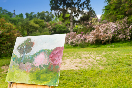Beautiful colorful sketch of a picture on painter's easel standing in a garden or a parkの写真素材