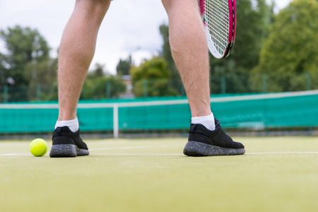 Male tennis player's legs during the game wearing a sportswear on green grass court outdoorsの写真素材