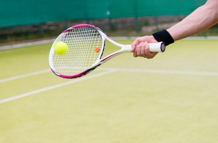 New tennis racket and ball in action at green tennis courtの写真素材