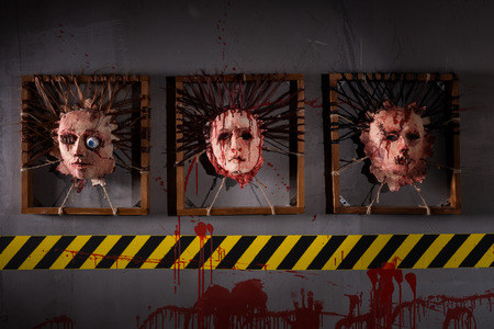 Ghastly skins from human heads stuck in square frames above yellow and black warning symbol