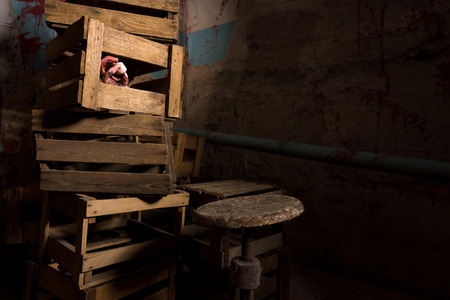 Frightening torso of a dead woman and wrinkled hand holding eyeball discarded amongst wooden boxes in a Halloween horror conceptの写真素材