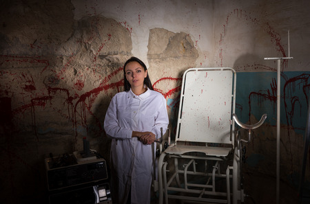 Female scientist in dungeon with bloody walls in a Halloween horror conceptの写真素材