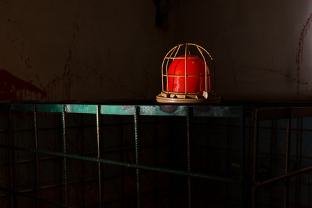 Red lamp on the iron cage behind blood splattered wall for concept about torture or scary Halloween themeの写真素材