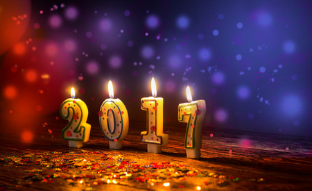 Burning candles number 2017 and colorful sprinkles with glittering red and blue blurred background, new year conceptの写真素材