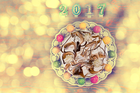 New year cake and macarons as a clock near candles number 2017 on colorful background, new year...