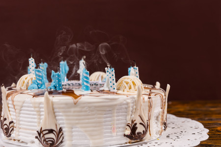 Homemade delicious birthday pie with lots of extinguished candles on white napkin, on wooden deskの写真素材