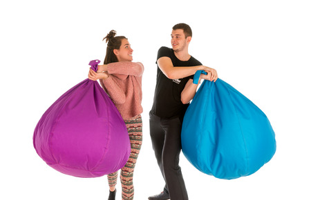 Young male and female fighting with beanbag chairs isolated on white backgroundの写真素材