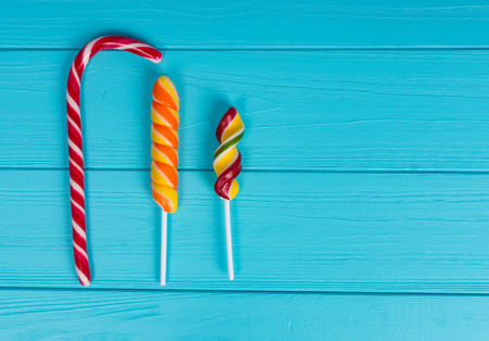 Three colorful tasty lollipops on wooden turquoise tableの写真素材