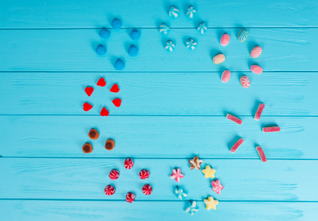 Many different delicious licorice candies and jelly candies are arranged in circles on wooden tableの写真素材