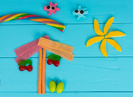 Funny picture of tasty jelly candies in the shape of cherries and trees on wooden turquoise table