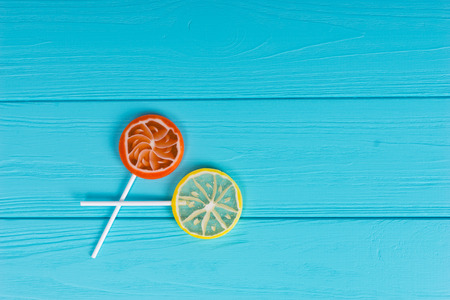 Small lollipops as an orange and lemon on wooden turquoise boardの写真素材