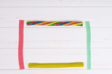 Colorful tasty licorice and chewy candies on wooden white board