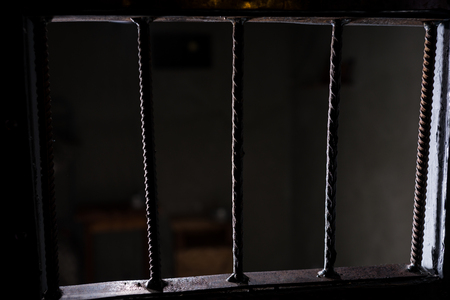View of the empty jail cell through the bars of the doors