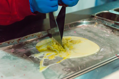 The process of preparing tasty thai natural ice cream with banana on special equipment at open food festivalの写真素材
