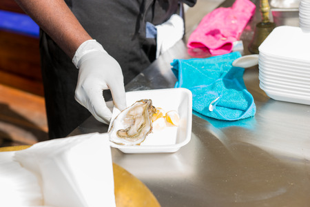 Close up of unrecognizable man holding open oyster at outdoor food festivalの写真素材