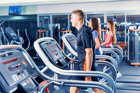 Young handsome fit man exercising on a treadmill at the bright modern gym