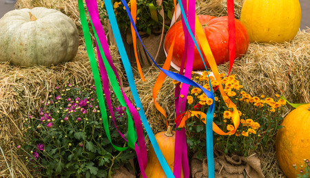 Harvest of pumpkins, squash, gourds and chrysanthemums arranged on haystacks near hanging multicolored ribbons, autumn and thanksgiving day conceptの写真素材