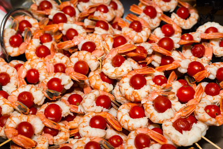 Appetizing cooked shrimps with tomatoes on skewers at food festival, food and beverage conceptの写真素材