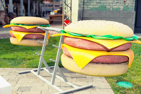 Barbell with toy burgers as weight plates outdoor on food festival. Food and beverages conceptの写真素材