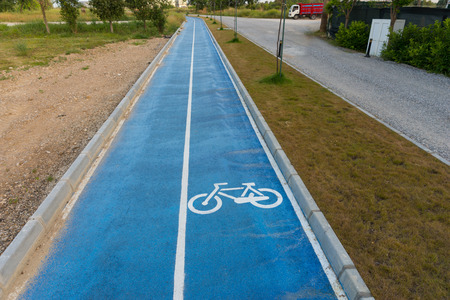 Painted bicycle icon on an asphalt road with a cycling track for sports enthusiasts in a straight receding view alongside a rural streetの写真素材