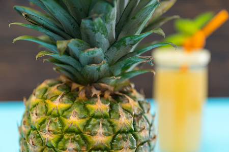 Close up detail of the skin of a whole ripe fresh tropical pineapple in a partial view with blurred glass of juice behindの写真素材