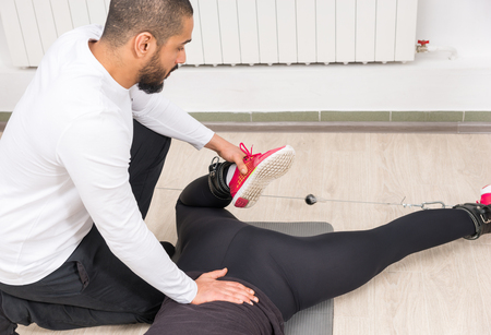 Trainer instructing woman in proper workout at gymの写真素材