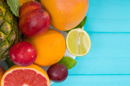 Healthy diet concept with fresh tropical fruit forming a close up side border on turquoise blue wood...