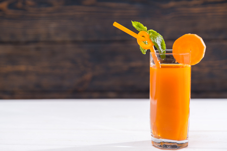 Tall glass of fresh carrot smoothie garnished with minto and served with a straw with copy spaceの写真素材