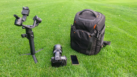 A camera, bag, gimbal, smart phone and video production equipment set up on a lush grass, turf background.の写真素材